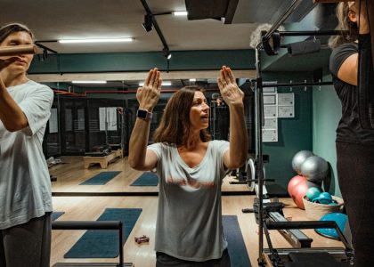 Pilates instructor guiding two women during a workout in a modern gym environment.