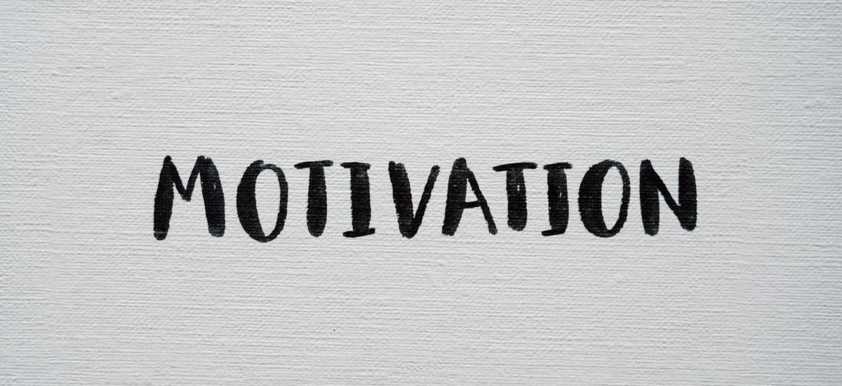 Inspirational word 'Motivation' in black on a white textured canvas background.